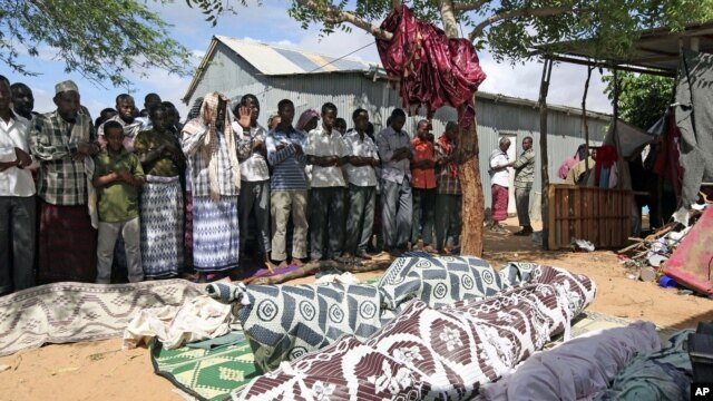 Relatives pray for the bodies of seven people killed during a raid by Islamists in Somalia's capital Mogadishu, May 8, 2012. 