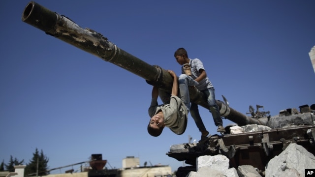 A boy looks back while he and another boy play on a Syrian military tank, destroyed during fighting with the Rebels, in the Syrian town of Azaz, on the outskirts of Aleppo, Sunday, Sept. 2, 2012.