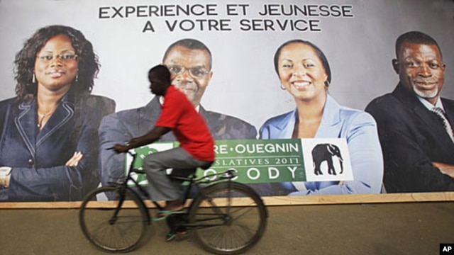 A cyclist rides past a campaign poster of candidates of the Democratic Party of Ivory Coast in Abidjan December 6, 2011. The slogan on the poster reads "Experience and youth at your service."