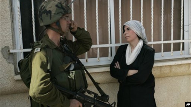 A Palestinian woman stands next to an Israeli soldier during a protest against the expansion of a Jewish settlement near the West Bank village of Nabi Saleh, Friday, Oct. 22, 2010.
