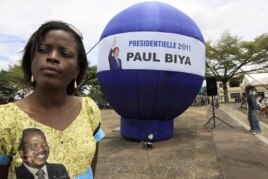 A supporter of Cameroon President Paul Biya stands next to a giant election campaign ball in Yaounde, Cameroon, October 8, 2011.