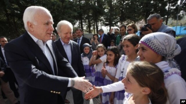 US Senators John McCain (R-AZ) (L) and Joseph Lieberman (D-CT) (2nd L) are greeted by Syrian refugee children during their visit at Yayladagi refugee camp in Hatay province on the Turkish-Syrian border, April 10, 2012.