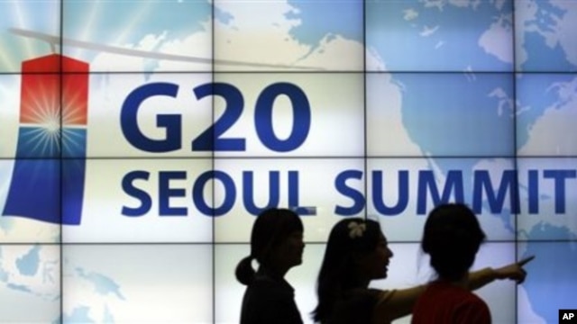 Women walk by a screen showing G20 Seoul Summit sign at the venue for the upcoming summit meeting, 02 Nov 2010