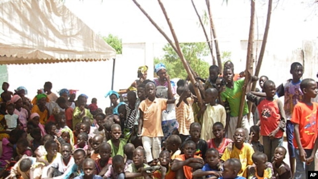 Kids from nearby villages gather at the Mbosse health clinic to watch a play on malaria prevention