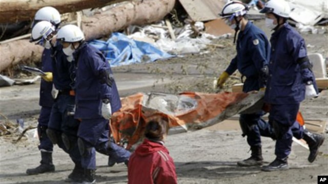 Police officers carry a body during a search and rescue operation in the earthquake and tsunami-devastated city of Rikuzentakata, Iwate Prefecture, northeastern Japan, March 23, 2011