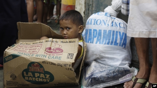  A Filipino boy sits inside an empty carton of noodles as he waits for his parents to receive relief goods, in Quezon City, Philippines, August 13, 2012. 