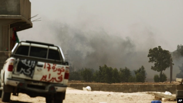 Smoke rises after a rocket exploded near a Libyan rebel fighter position on the outskirts of Zlitan near Misrata's western front line