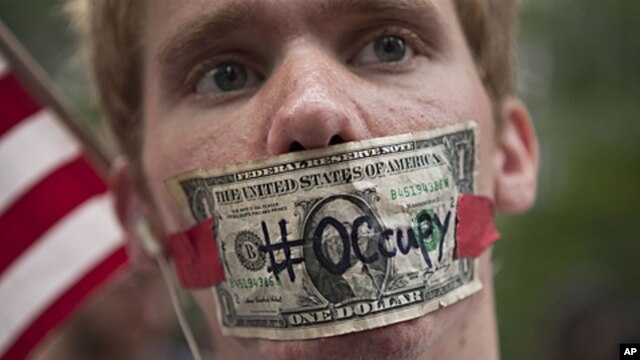 Occupy Wall Street demonstrator with a dollar bill taped over his mouth, Zuccotti Park, New York, Oct. 10, 2011.