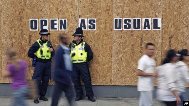 Police officers from Wales patrol outside a boarded up shop in Streatham, south London, August 10, 2011