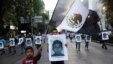 FILE - Demonstrators carry photos of the 43 missing trainee teachers as a boy waves a Mexican flag, with its green and red parts replaced with black as a sign of mourning, during a march in support of  the students in Mexico City, Dec. 6, 2014.