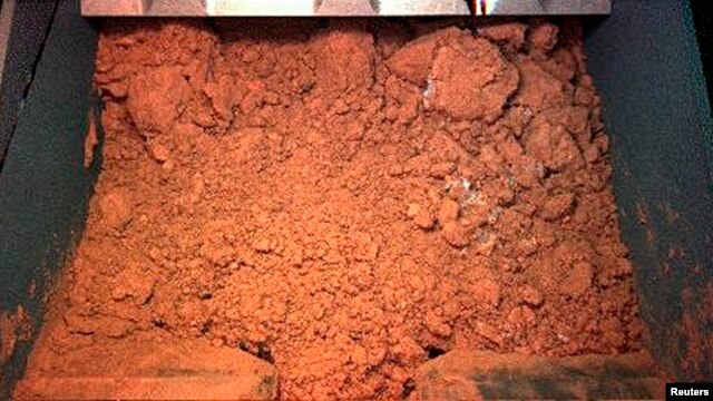 Martian surface material captured by NASA's Phoenix Mars Lander's Robotic Arm Camera, during its first test dig and dump mission, June 1, 2008.