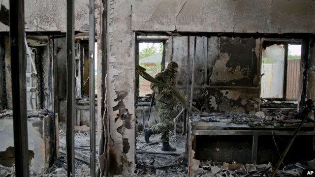 A pro-Russian rebel carries items seized from an Ukrainian border troops military unit in Luhansk, eastern Ukraine, June 4, 2014. 