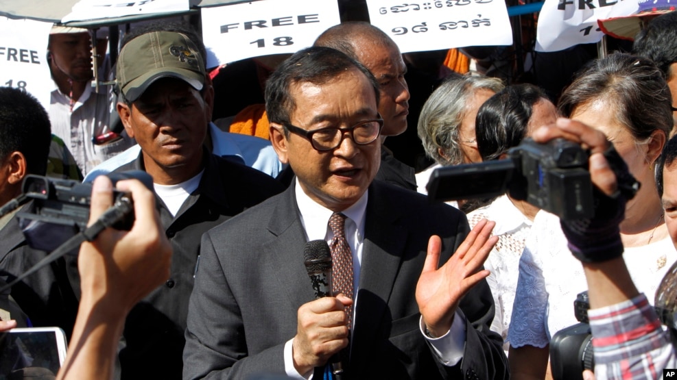 Opposition leader of Cambodia National Rescue Party Sam Rainsy, center, delivers a speech during a gathering to mark Human Rights Day, in front of National Assembly, in Phnom Penh, Cambodia, Wednesday, Dec. 10, 2014. (AP Photo/Heng Sinith)