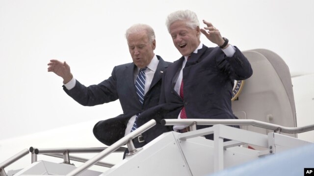 El vicepresidente Joe Biden acompaña al presidente Bill Clinton, mientras descienden cuidadosamente del avión durante una tormenta en Youngstown, Ohio. Tanto Romney como Obama suspendieron su agenda personal de campaña por la arremetida de 'Sandy'.