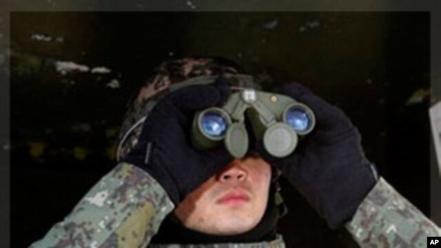 A South Korean Army soldier uses binoculars to watch Northern side after news reporting about the death of North Korean leader Kim Jong Il at a guard post in the demilitarized zone between South and North Korea in Cheolwon, South Korea, Monday, Dec. 19, 2