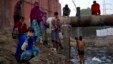 FILE - Indian men attend to their morning chores next to a sewage canal before they leave for work early morning in New Delhi, India, Dec. 12, 2014.