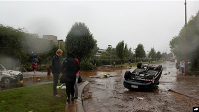 People survey the damage after a flash flood tossed vehicles down a street in Toowomba, Australia, 10 Jan 2011