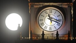 A supermoon rises next to a clock on top of the Palace of Culture in Warsaw, Poland, Sunday, Aug. 10, 2014.