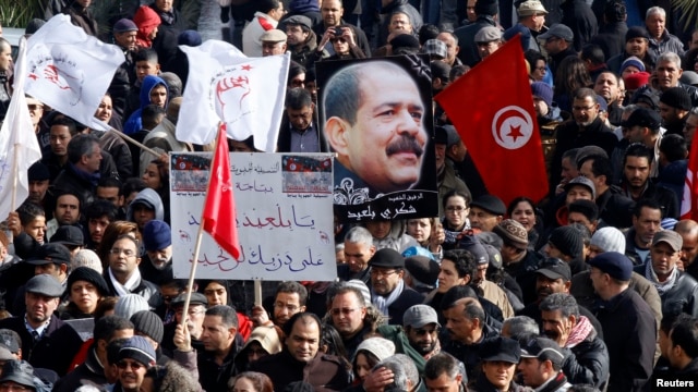 Tunisians hold a placard with an image of the late secular opposition leader Chokri Belaid during his funeral procession in the Jebel Jelloud district in Tunis, February 8, 2013. 