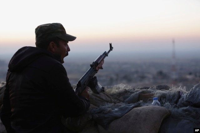 A Kurdish fighter, known as a peshmerga, yawns as he stands guard on the frontline in Sinjar, Iraq, Friday, Nov. 13, 2015.