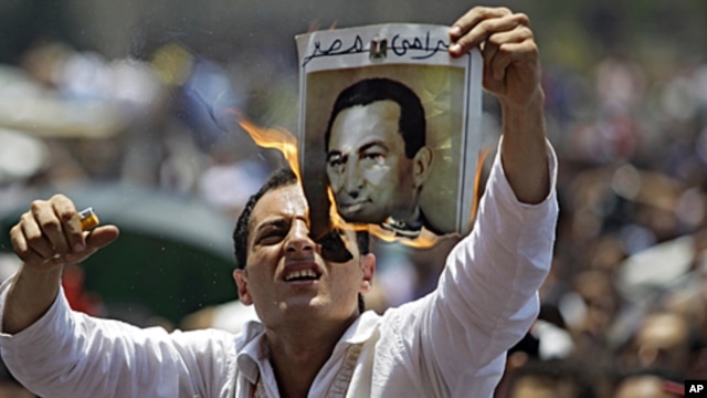 A man burns a picture of ousted Egyptian president Hosni Mubarak during a rally after Friday prayers in Tahrir Square, Cairo,  July 1, 2011