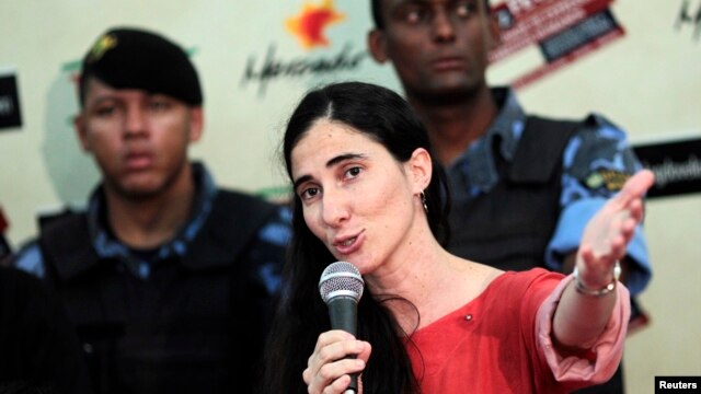 La disidente cubana Yoani Sánchez, custodiada por guardias de seguridad ofrece una conferencia de prensa entre simpatizantes y manifestantes que apoyan el régimen cubano durante su primer día de visita en Brasil.  
