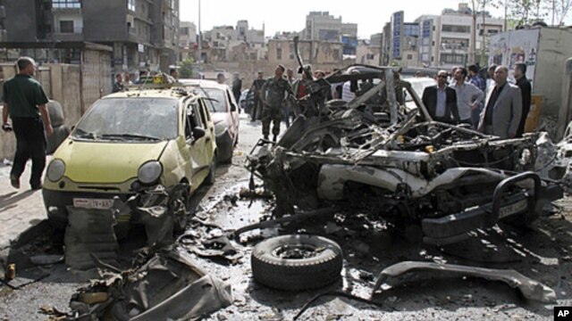 People look at destroyed and damaged vehicles after an explosion on al-Thawra Street in Damascus, Syria, May 5, 2012. 