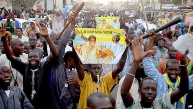 Disciples of Cheikh Béthio Thioune chant and carry clubs on a marchon March 17, 2012 in Dakar in support of President Abdoulaye Wade. They say the clubs were for self defense against anti-Wade activists.
