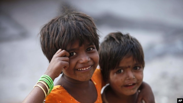 Two Indian girls react to the camera as they play on a street outside their roadside shanty, on International Day of the Girl Child in Hyderabad, India, Oct. 11, 2012.