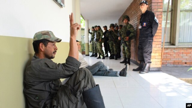 Un rebelde de las FARC capturado por la policía hace la señal de la victoria. Seis policías fueron asesinados por guerrilleros en el sureste de Colombia.