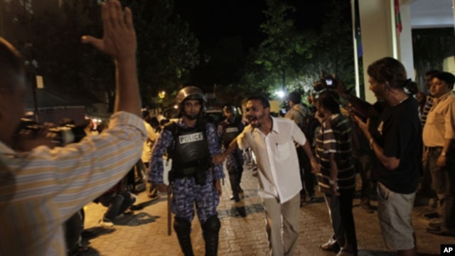 Supporters of Maldives' former President Mohamed Nasheed taunt a police officer during a protest in Male, Maldives, Sunday, Feb. 12, 2012.