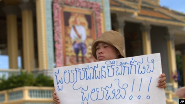 Khek Chan Raksmey of Boueng Kak holds a protest sign as she participates in a rally to ask King Norodom Sihamoni to help release of villagers including her mother in front of Royal Palace in Phnom Penh, Monday, June 11, 2012. The villagers were arrested w