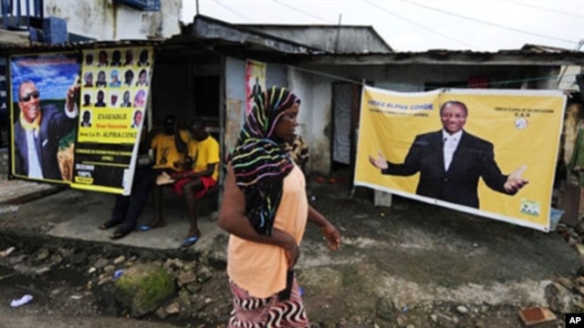 A woman walks in front a poster for Guinean presidential candidate, Alpha Conde, hung in front of the home of supporter for his party (file photo)