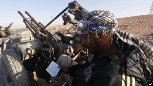 An anti-Gaddafi fighter reads the Koran at a checkpoint north of Bani Walid. (file photo)