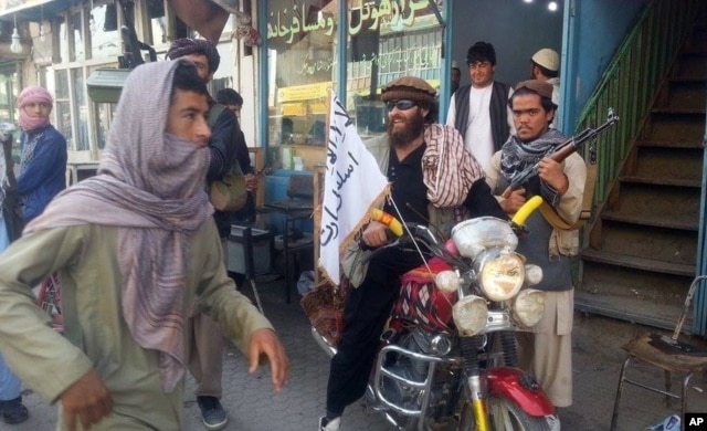 Chiến binh Taliban ngồi trên xe gắn cắm cờ Taliban trên đường phố ở thành phố Kunduz, ngày 29/9/2015.