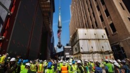 Giới truyền thông và công nhân chứng kiến đỉnh của Tòa nhà Trung tâm Thương mại được nâng lên để hoàn tất công đoạn cuối 