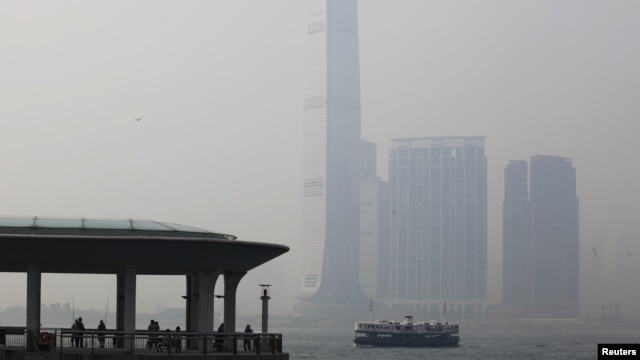 People rest at a ferry pier at the financial Central district under hazy weather in Hong Kong August 1, 2012. In the background, is the city's highest building, the International Commerce Centre in Kowloon peninsula. 