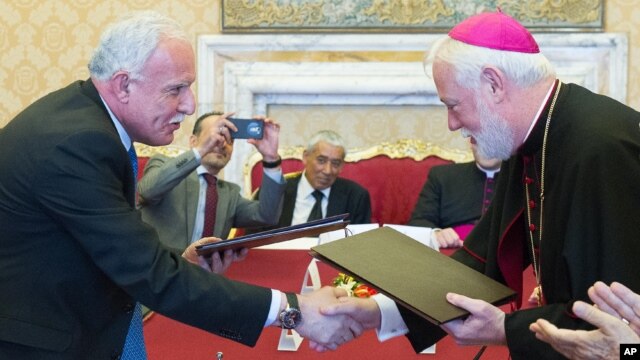 Vatican Foreign Minister Paul Gallagher, right, and his Palestinian counterpart, Riad al-Malki, shake hands after signing a treaty — covering church operations in parts of the Holy Land under Palestinian control — at the Vatican, June 26, 2015.