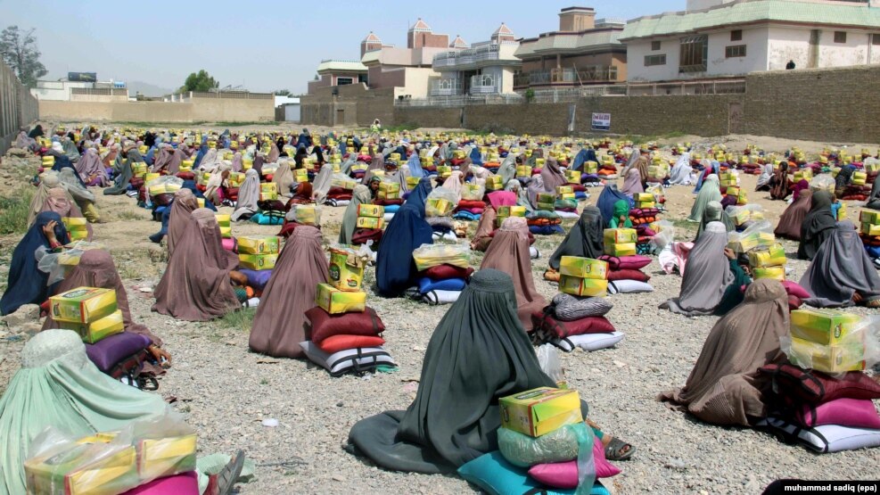 FILE - Afghan burqa-clad women sit after they received ration aid in Kandahar, Afghanistan, May 4, 2016. 