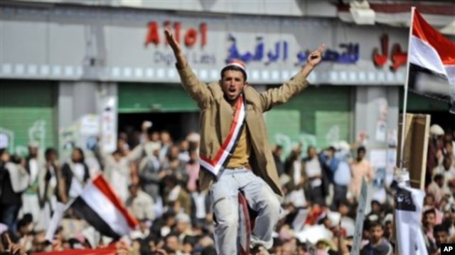 An anti-government protestor sitting on a traffic sign reacts as the bodies of demonstrators who were killed on Friday's clashes with Yemeni security forces, arrive during their funeral procession in Sanaa, Yemen, March 20, 2011