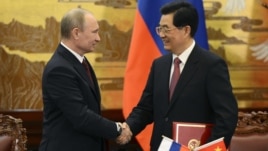 China's President Hu Jintao and Russian President Vladimir Putin shake hands in Beijing, June 5, 2012.