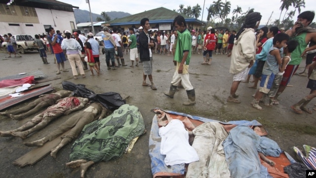 Residents pass by bodies recovered from flashflood in New Bataan, Compostela Valley province, southern Philippines, December 5, 2012.