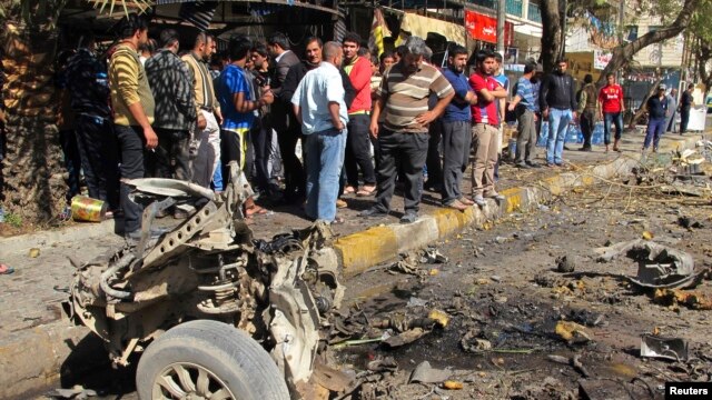 Residents are seen inspecting the site of a car bomb attack in the Karrada district in Baghdad February 17, 2013.