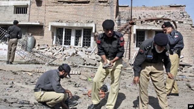 Pakistani police officers collect evidence from the site of a bomb explosion in Peshawar, Pakistan, May 20, 2011