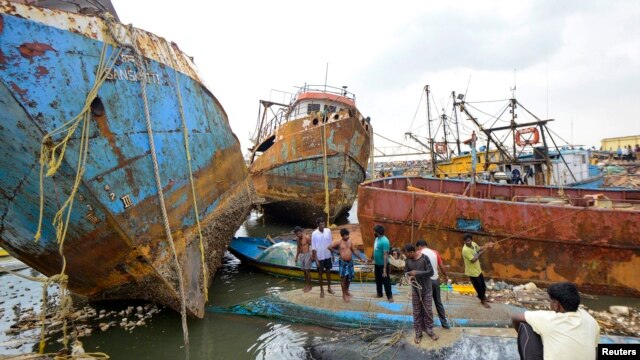 Cư dân đứng trên thuyền bị hư hỏng vì bão Hudhud tại thành phố miền nam Visakhapatnam ở Ấn Độ, ngày 13/10/2014.