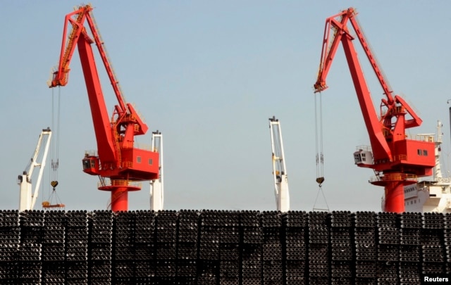 FILE - Piles of steel pipes to be exported are seen in front of cranes at a port in Lianyungang, Jiangsu province, March 7, 2015.