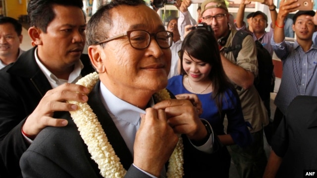 FILE - Sam Rainsy, foreground, leader of the opposition Cambodia National Rescue Party (CNRP), receives a garland of jasmine upon his arrival at Phnom Penh International Airport in Phnom Penh, Cambodia, Aug. 16, 2015.