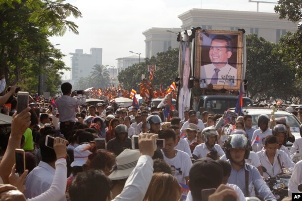 Cambodia mourners take photos as they watch the funeral procession for Cambodian leading government critic Kem Ley, whose portraits are displayed on a vehicle, in Phnom Penh, July 24, 2016.