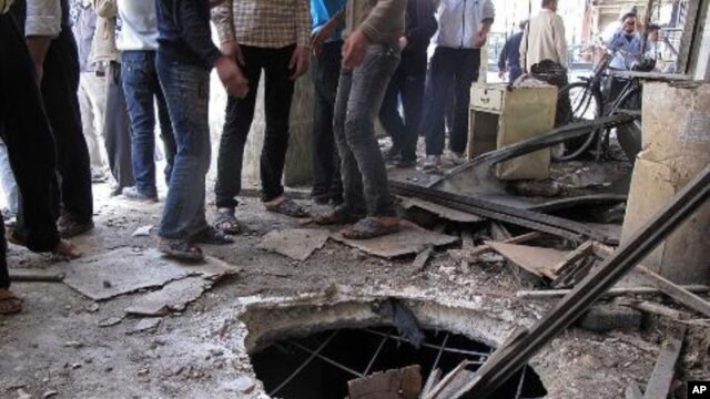 Syrians gather near a crater from a tank shell in a neighborhood of the capital, Damascus, after a raid by Syrian troops killed several rebels and civilians, April 5, 2012. 
