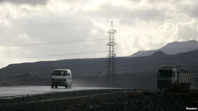 Vehicles drive past a high-voltage power line tower on a highway south of the Yemeni capital Sana'a February 26, 2010.